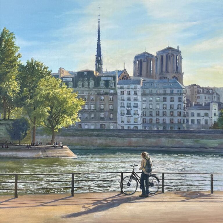 Person with a bicycle overlooks the river in front of historic buildings and the Notre-Dame Cathedral.