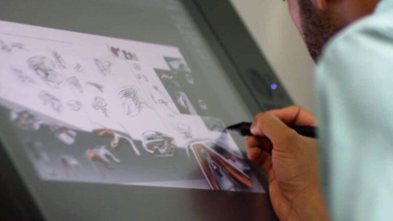 Person sketching multiple head and face designs on a digital drawing tablet using a stylus.