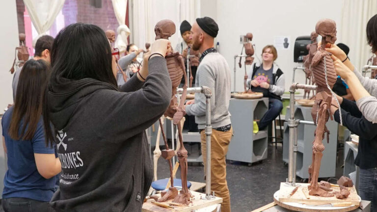 People working on skeletal sculptures in a classroom or workshop setting.