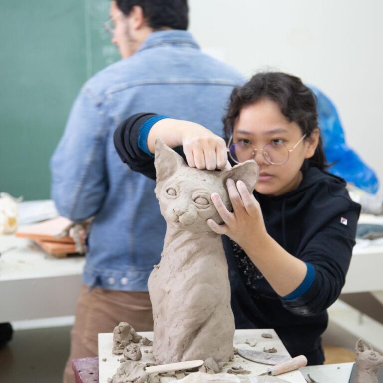 Woman sculpting a cat out of clay