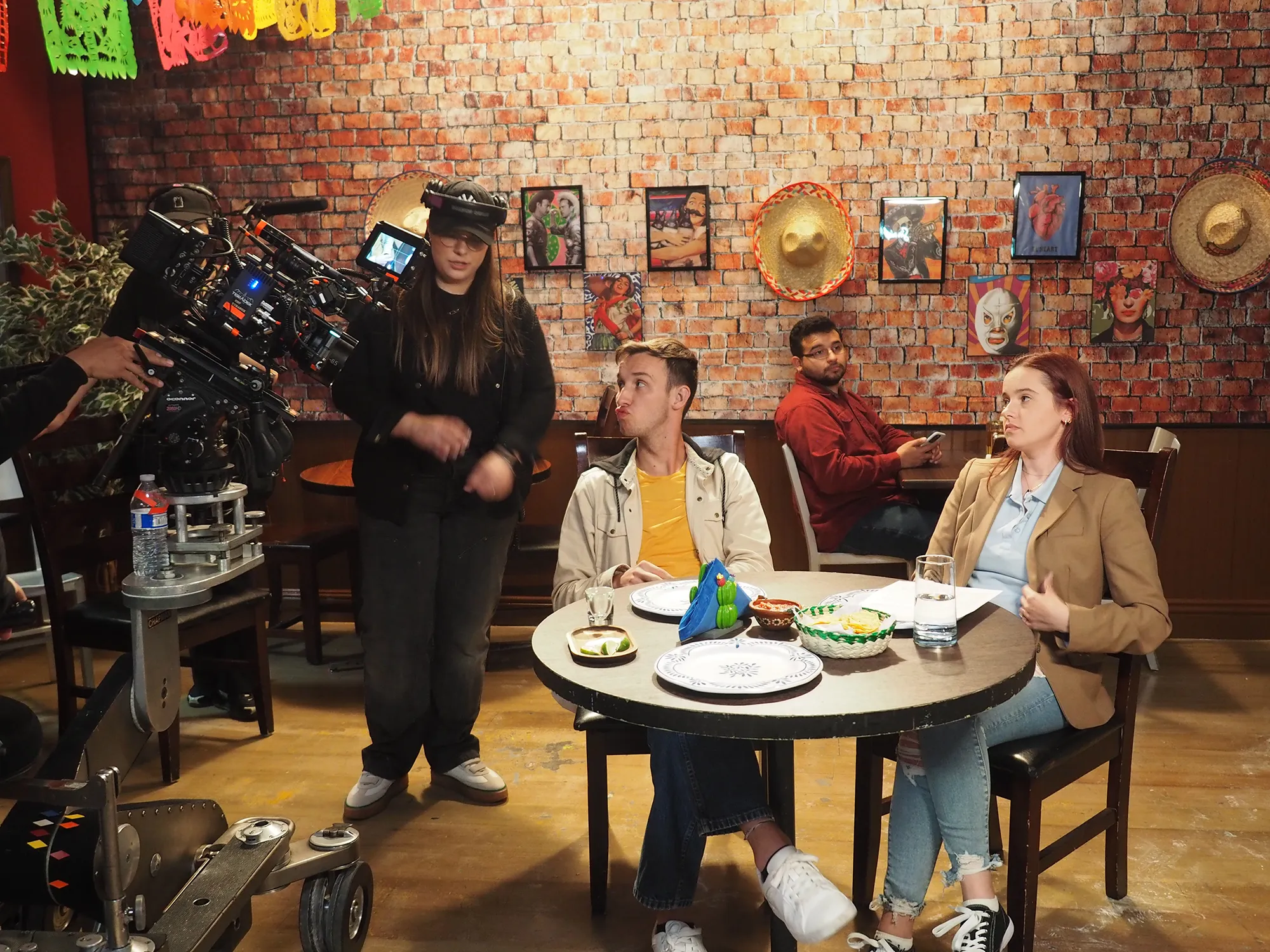 People sitting at a restaurant table with decorations on a brick wall behind them.