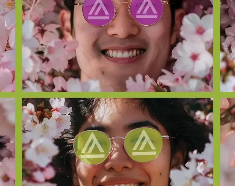 Six diverse people wearing colorful sunglasses smiling among pink cherry blossoms.