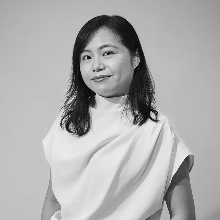 A woman with shoulder-length hair wearing a sleeveless white top, looking at the camera.