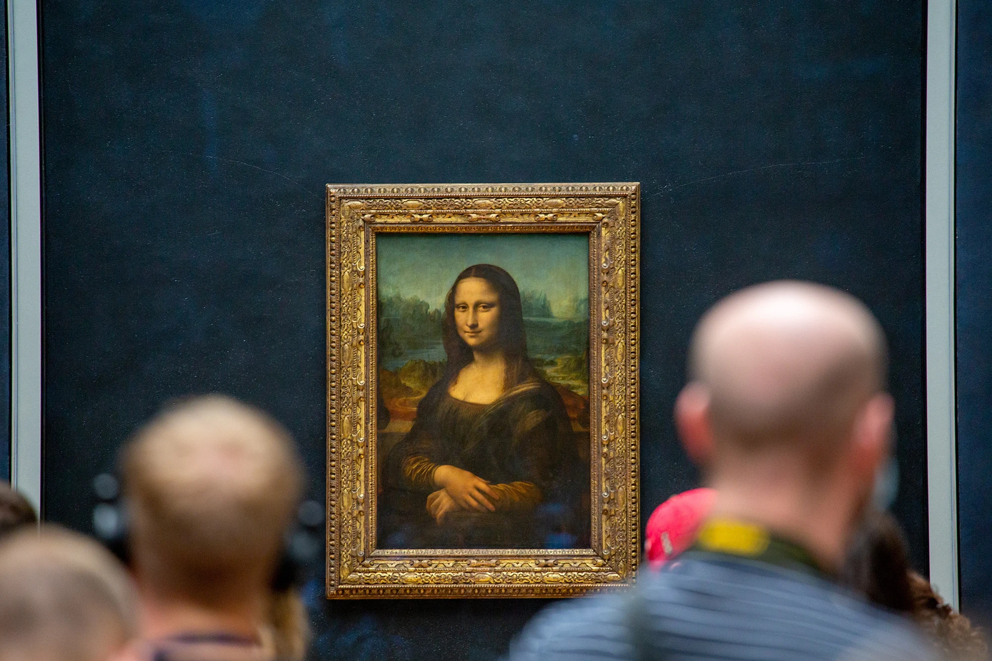 Visitors observing the Mona Lisa painting at the Louvre Museum in Paris.