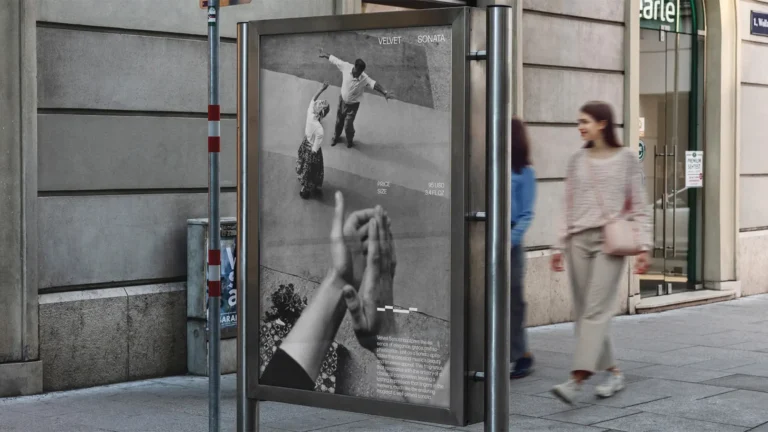 Black-and-white advertisement on street panel showing people reaching upward, with bold hands in foreground and couple on a wall behind.