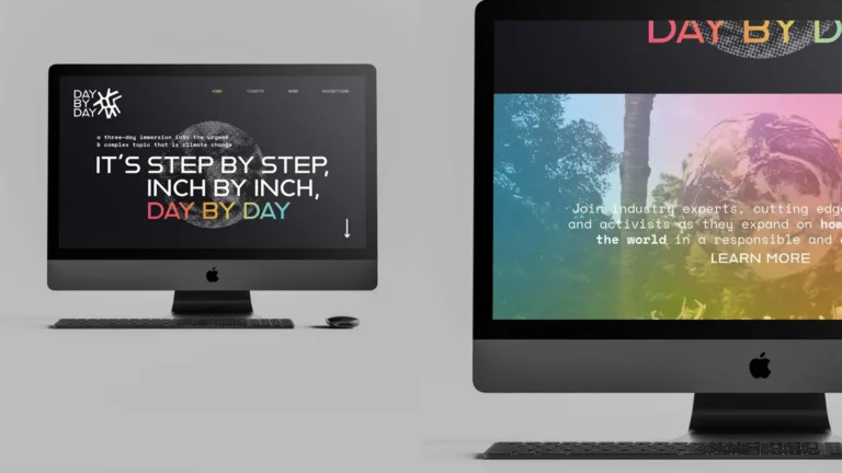 Two large computer monitors showing colorful website designs on dark screens, with one desktop and a second side-by-side.