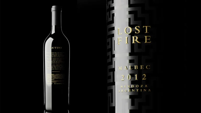 Bottle of wine with gold label beside a geometric black-and-white book cover reading LOST FIRE, Malbec 2012 Argentina