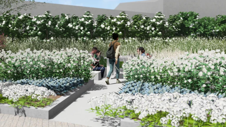 People walk and sit among lush white-flowered shrubs in a garden courtyard.