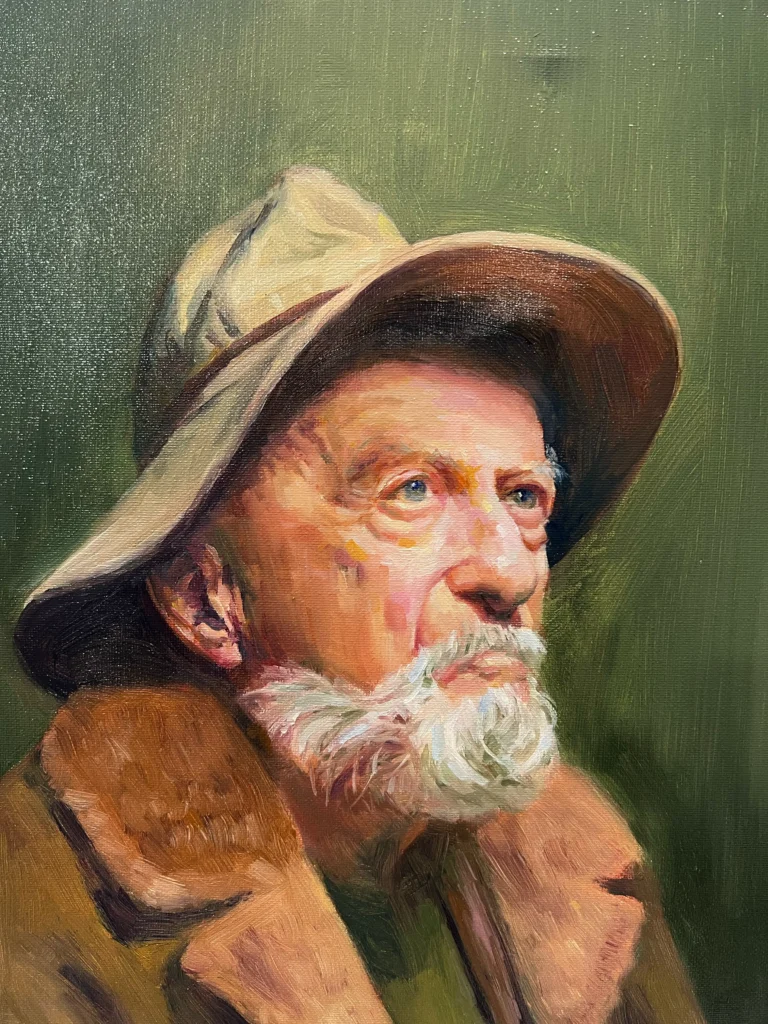 Elderly man with white beard wearing hat and brown coat