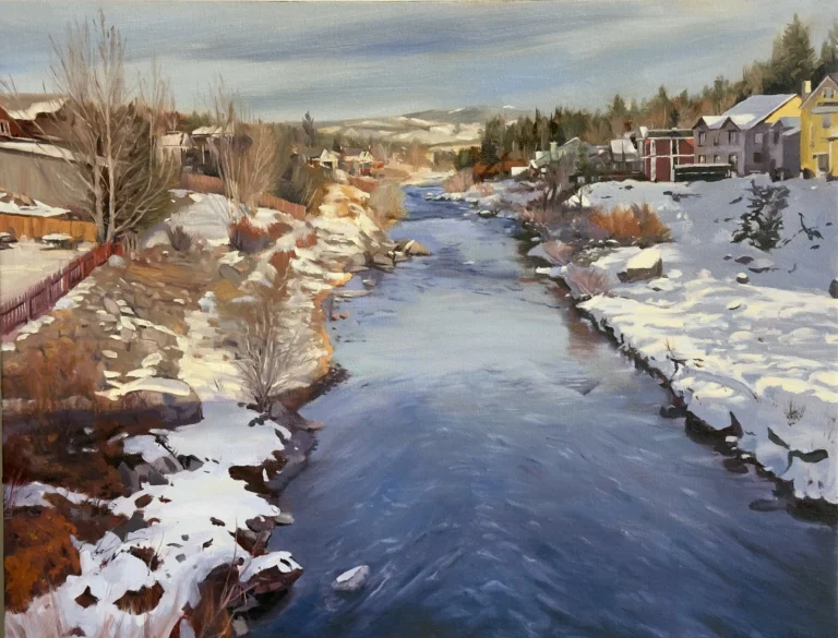 Snowy river town with houses along banks and distant hills.