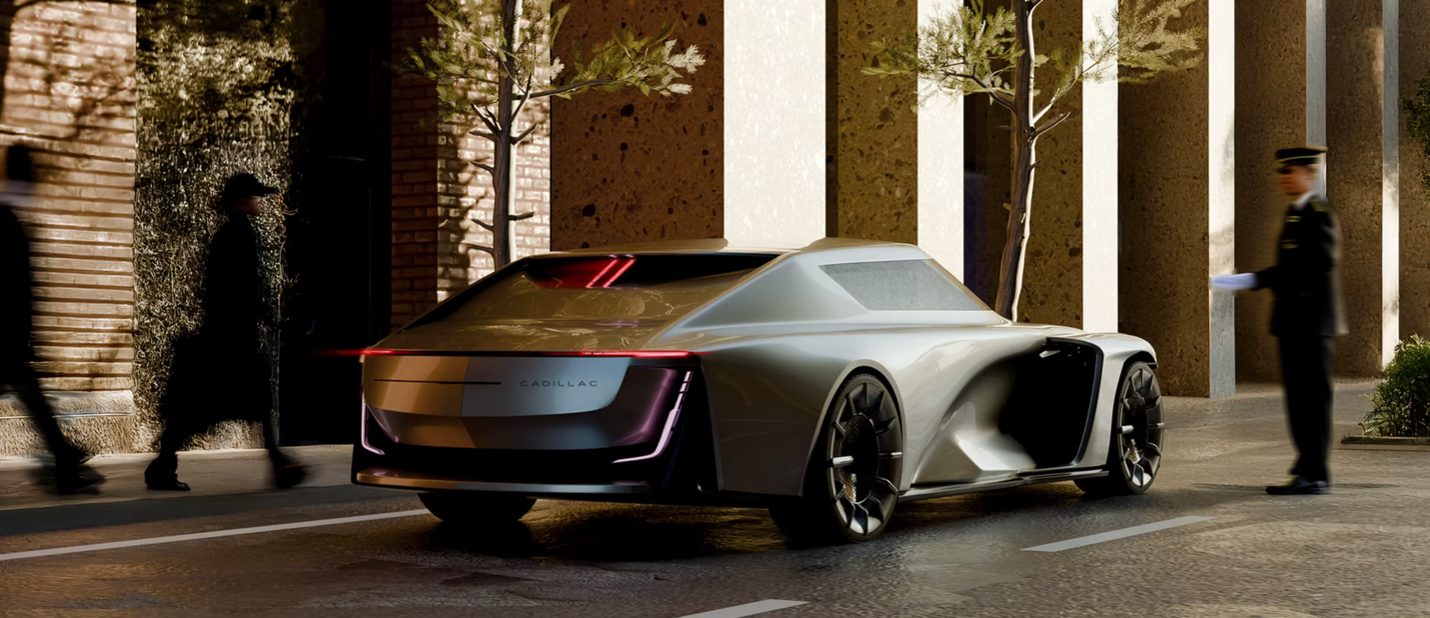 Futuristic silver Cadillac concept car on city street at night with pedestrians nearby