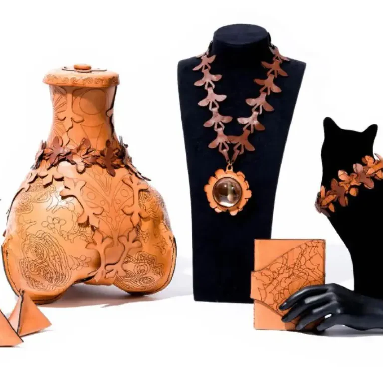 Orange carved ceramic vases and jewelry displayed on black velvet stands and mannequin.