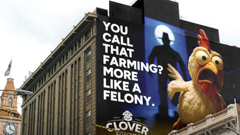 Oversized mural of bold white text and a chicken character on black wall