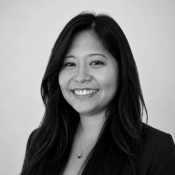 Smiling woman with long dark hair wearing a blazer and necklace