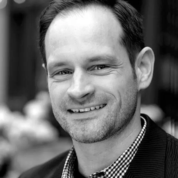 Smiling man in checkered shirt and blazer outdoors