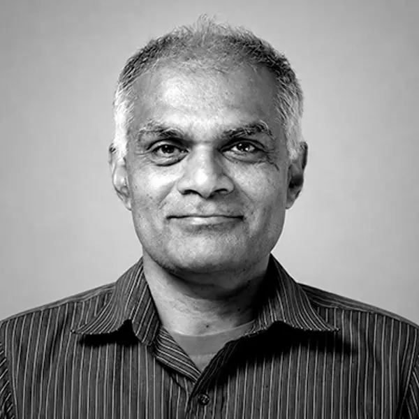 A smiling man with short gray hair wearing a striped collared shirt.