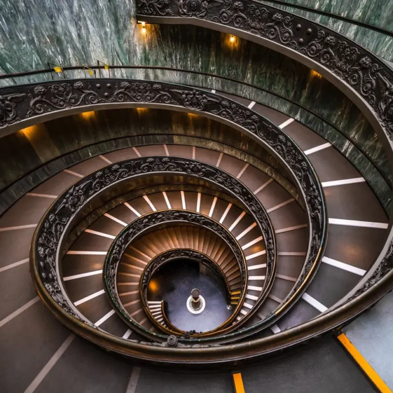Spiral ornate staircase descending in circular view with green marble walls