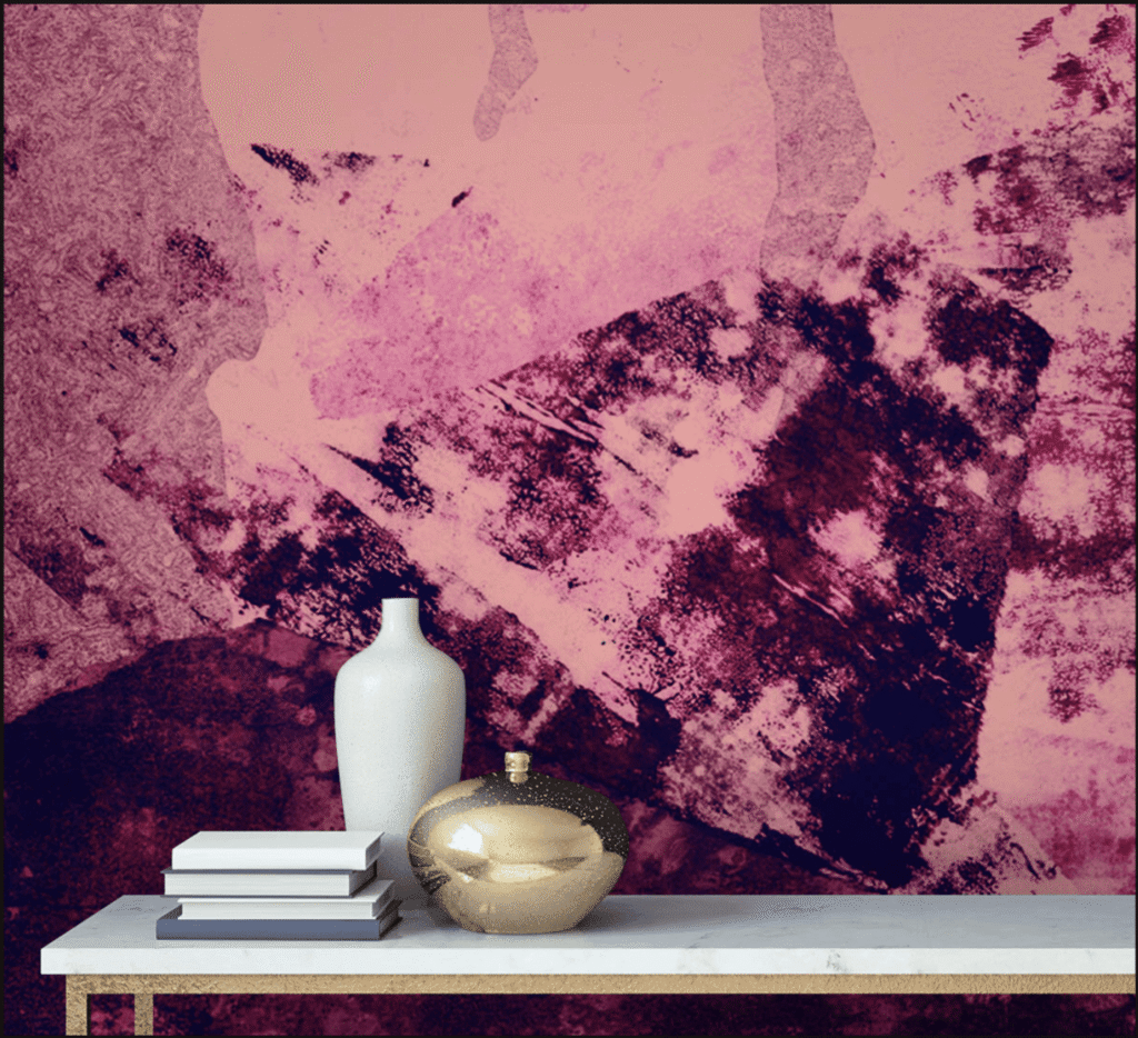 A white vase and a reflective gold orb rest on a marble table, accompanied by stacked books, against a textured pink and purple abstract wall.